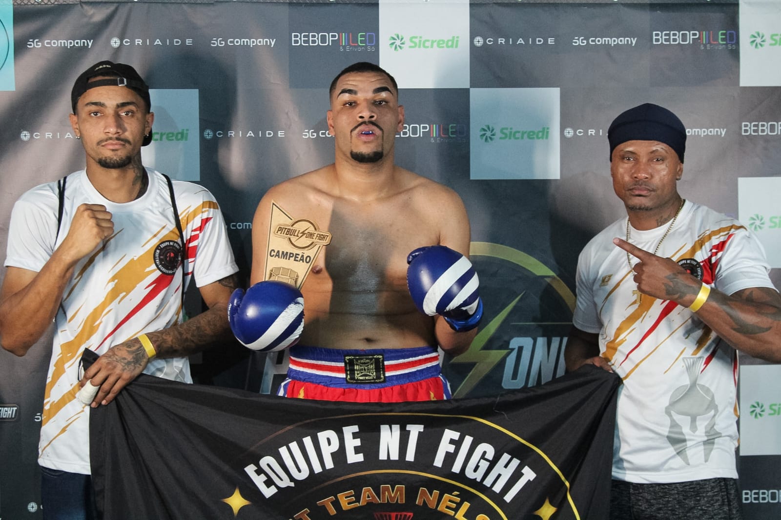 Atleta da NT Fight campeão com troféu e bandeira da academia