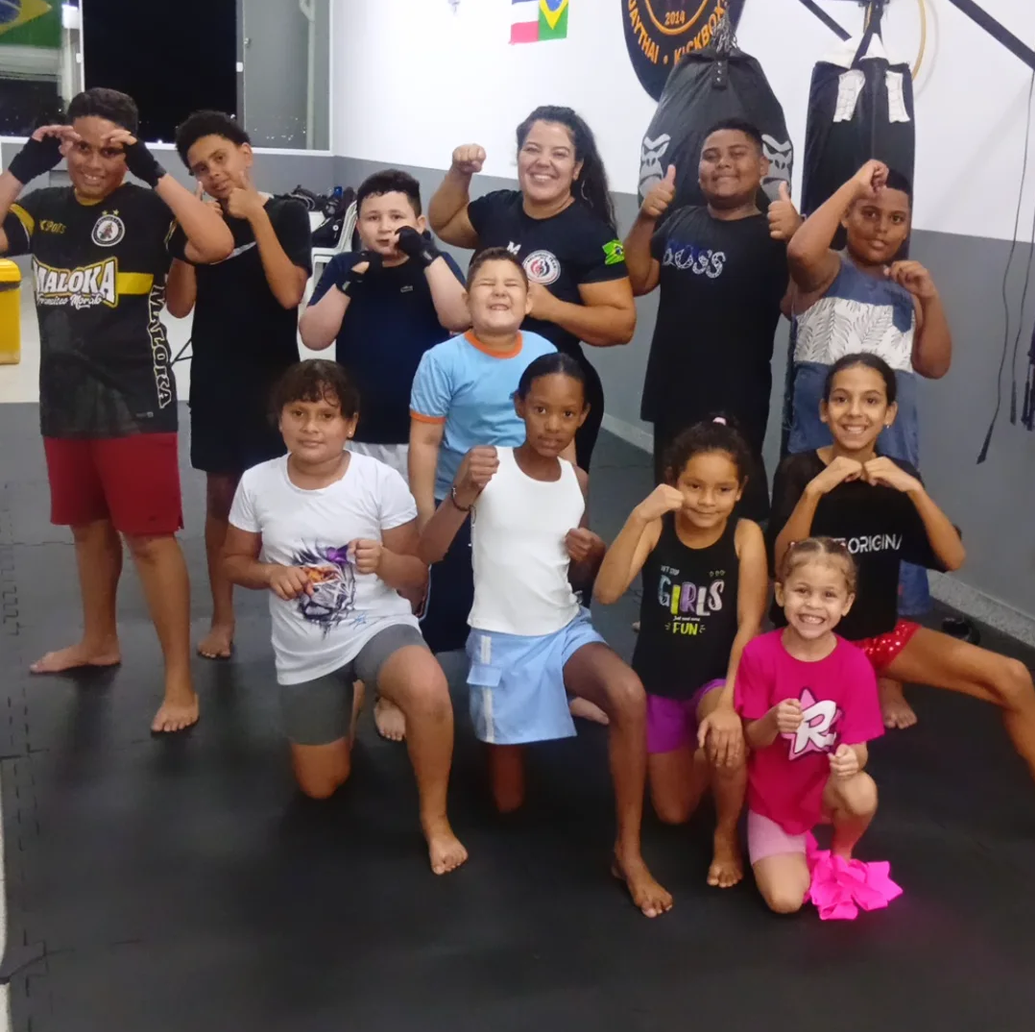 Crianças da turma kids sorrindo em guarda ao lado da instrutora Keilla